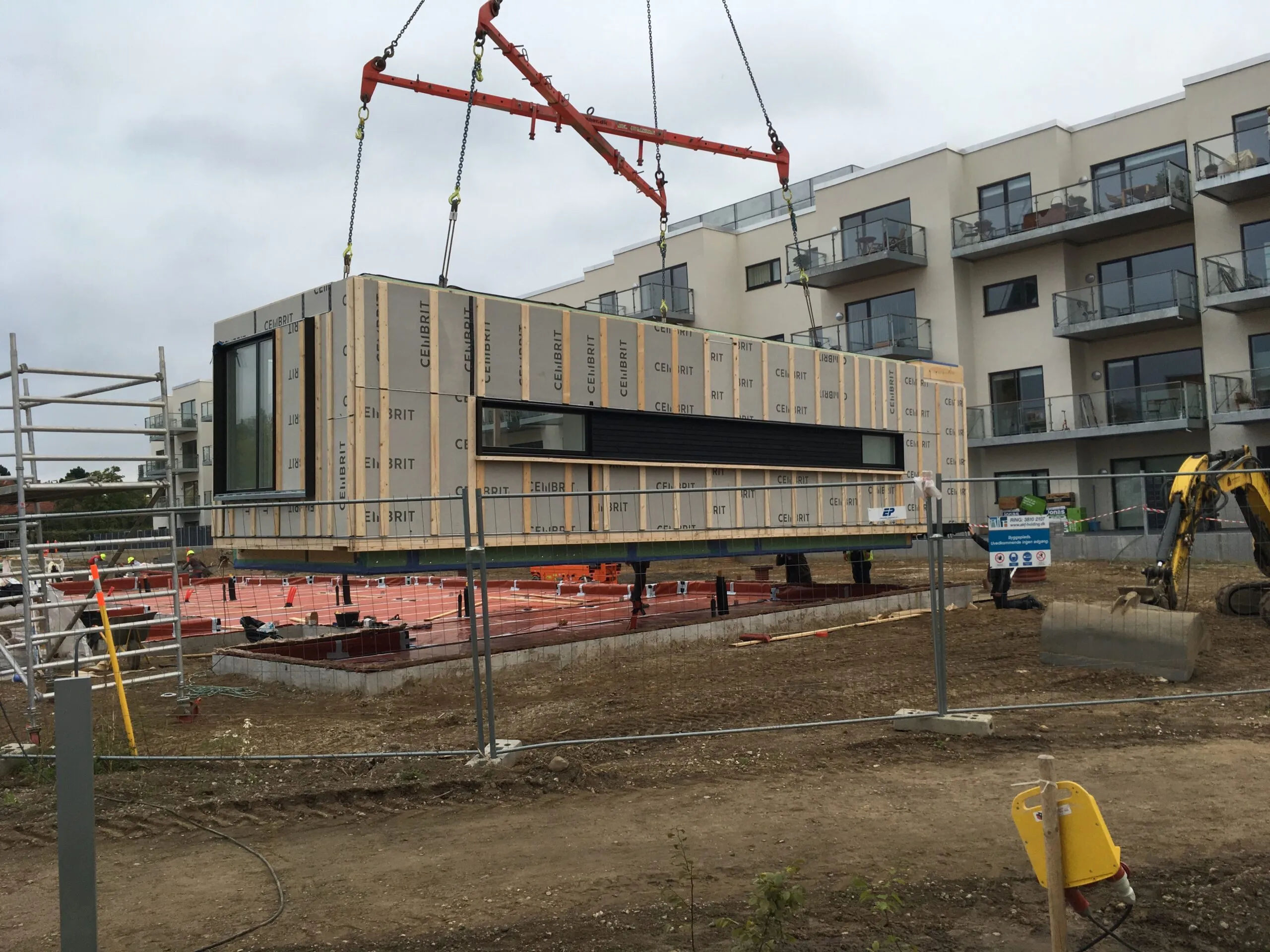 Præfabrikeret boligmodul løftes på plads med kran på byggepladsen ved Bagsværdlund