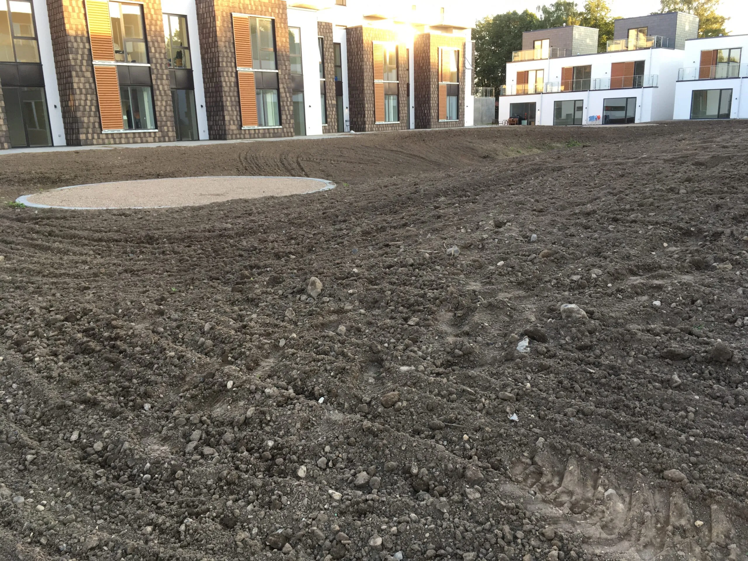 Ujævn jord foran nybyggede rækkehuse og lejligheder inden anlæg af grønt fællesareal